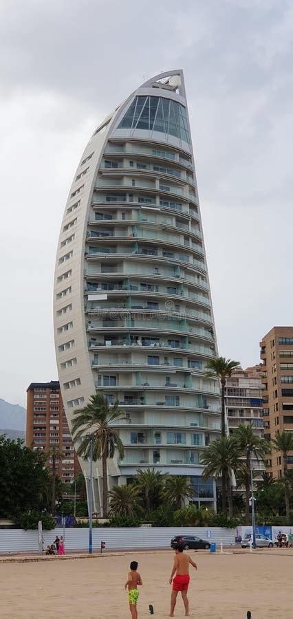 A Modern Curved Building With Multiple Balconies Located Near A Sandy