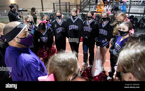 Masked Up Cedar Ridge High School Cheerleaders Rally Around Their Coach Before A District 25 6A High School Football Game On A Chilly Night At Dragon Stadium In Round Rock Texas Usa Stock