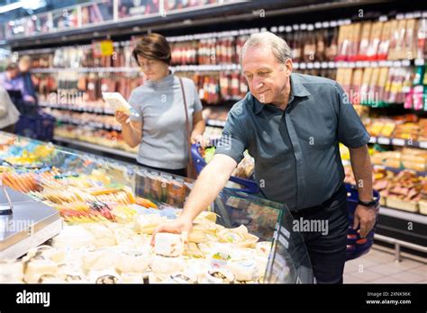 Older Man Picking Out Fresh Cheese To Buy In Grocery Store Stock Image Older Man Picking Out Fresh Cheese To Buy In Grocery Store Stock Image