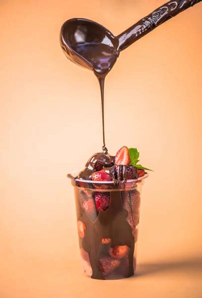 Pouring Fresh Strawberries In Plastic Cup With Melted Chocolate On